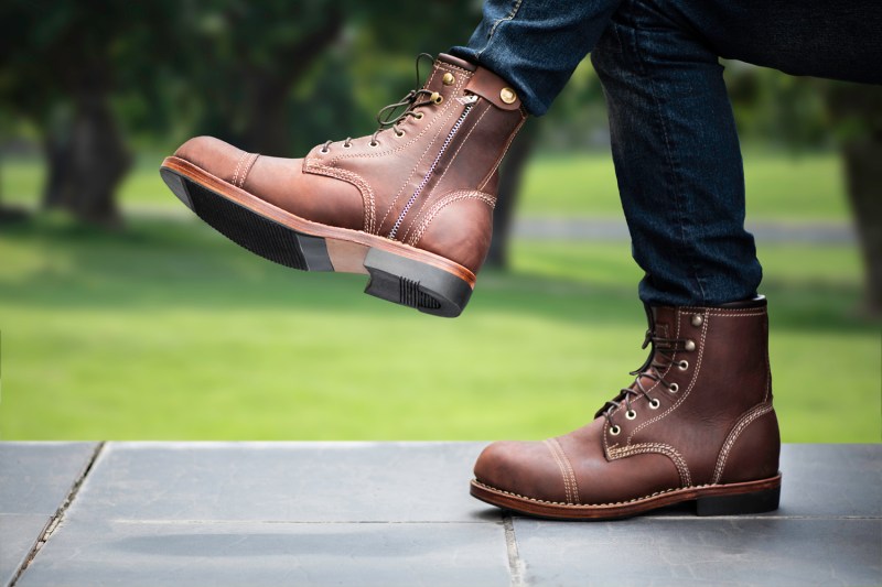 A man in jeans and brown boots at a park.