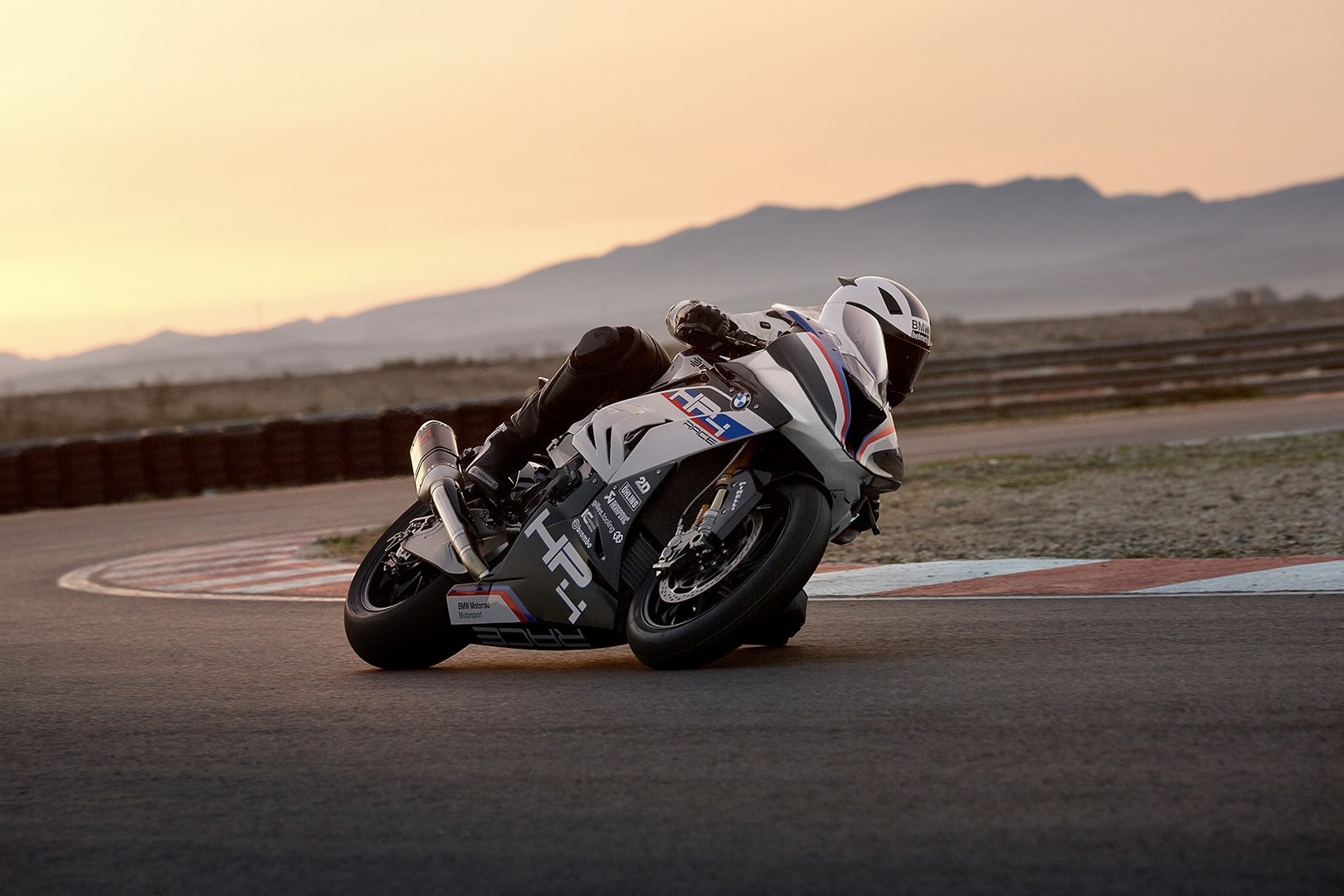 Ride taking the BMW HP4 Race around a track with mountains in the back.