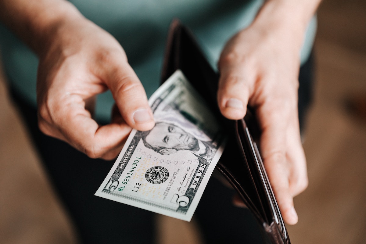 a man taking a $5 from a black wallet